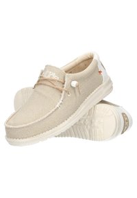 Zapatillas de lona beige sin cordones con bordes deshilachados, suela de goma blanca y acentos marrones. Presentan un cordón en tonos tostados y un logo en el lateral.