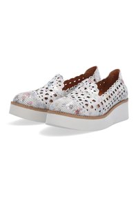 White perforated slip-on shoes with a floral pattern and scalloped edges, featuring a thick white platform sole and brown insole.
