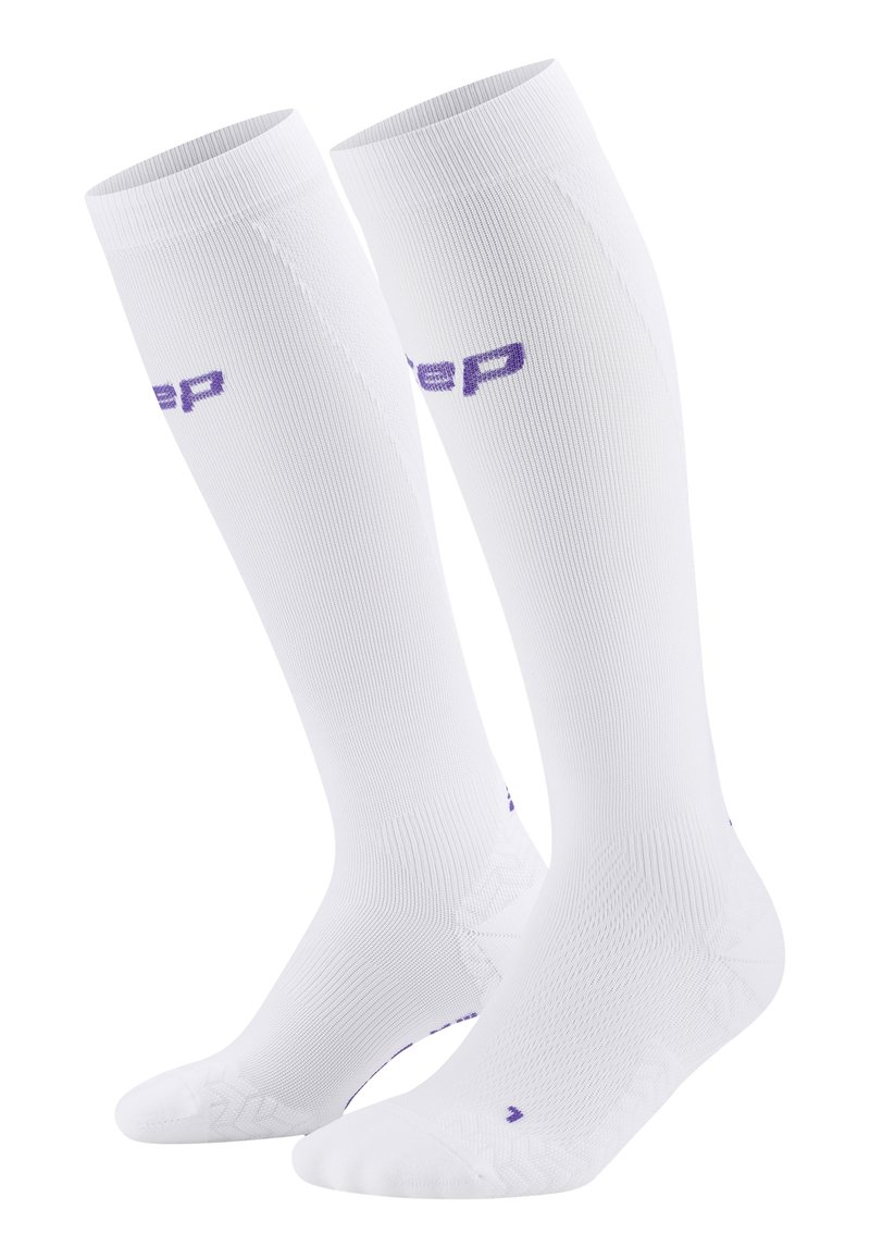 Calze bianche al ginocchio con texture a costine, tallone e punta rinforzati, e logo viola. Tessuto morbido, progettato per comfort e sostegno.