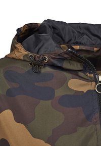 Camouflage-patterned jacket with a high collar, drawstring hood, zipper closure, and textured fabric in earthy tones of green, brown, and black.