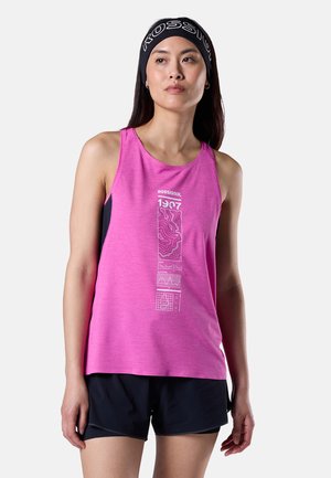 Žena v růžovém tílku Rossignol s grafickým designem a černých šortkách, mírně se dívá stranou, stojící před jednoduchým pozadím.