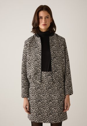 Schwarz-cremefarben gemusterte Jacke mit passendem Rock, mit kurzem Schnitt, Reißverschluss und strukturierter Stoffqualität. Lange Ärmel inklusive.