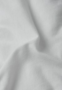 Biały materiał o gładkiej fakturze, z widocznym skręconym i złożonym wzorem. Światło odbija się miękko, co sugeruje lekki materiał.