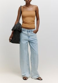 Braun gestreifter Tanktop, hellblaue weit geschnittene Jeans, schwarze geflochtene Tasche mit Fransen, schwarze Sandalen. Einfaches Design, lässige Passform.