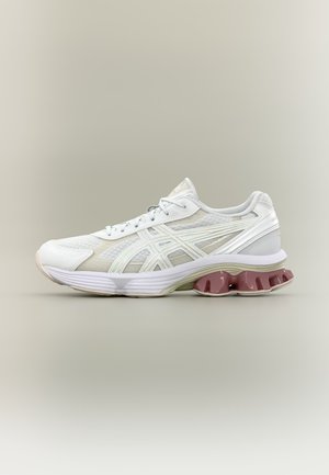 Witte sportschoen met bovenwerk van mesh, vetersluiting, kenmerkende zijstrepen en gesegmenteerde bordeauxrode demping in de zool, weergegeven op een neutrale achtergrond.