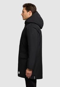 Black insulated parka with a hood, featuring a straight cut, side pockets, and a subtle logo on the sleeve. Smooth fabric texture.
