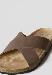 Braune Ledersandale mit gekreuzten Riemen, strukturiertem beigem Fußbett, Kork-Mittelsohle und schwarzer Gummilaufsohle.