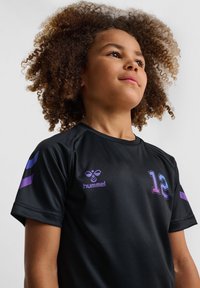 Zwarte sporttrui van lichtgewicht stof, met paarse accenten, het nummer 12 en een logo op de borst en schouders.