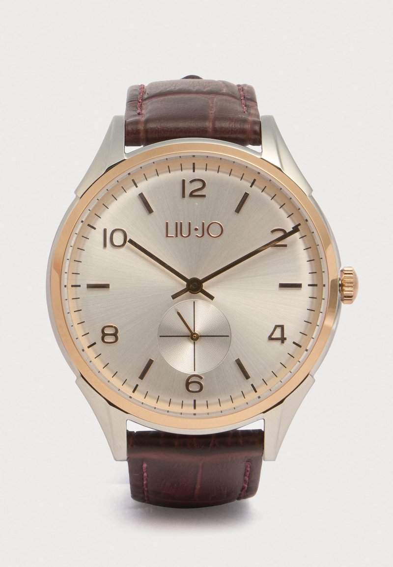 Ρολόι Liu Jo με γυαλιστερό ασημένιο καντράν, δερμάτινο λουράκι σε καφέ χρώμα με κροκοδείλια υφή και ροζ χρυσές λεπτομέρειες. Διαθέτει δείκτες ωρών και υποκαντράν.