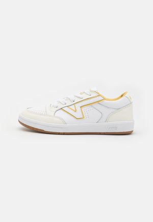 Zapatillas de cuero blancas con acentos amarillos, paneles laterales texturizados y suela de goma. Incluye detalles de costura y un diseño de cordones.