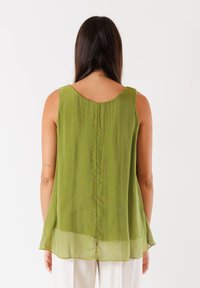 Blusa senza maniche verde oliva con scollo arrotondato, tessuto fluido e orlo curvo, caratterizzata da una cucitura verticale sul retro.