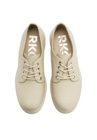Beżowe skórzane buty o teksturowej powierzchni, okrągłym nosku, z trzema oczkami i jasnymi sznurówkami. Logo na wkładce w metalicznym druku.