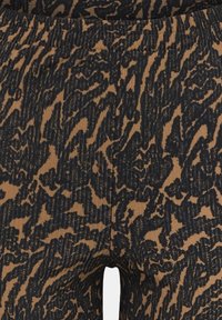 Kalhoty z ribované tkaniny s černým a hnědým abstraktním vzorem, s elastickým pasem a hladkou texturou.