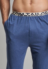 Miestne modré py�žamo s elastickým pásom s logom "TOM TAILOR". Vyrobené z mäkkej tkaniny s uvoľneným strihom a bočnými vreckami.