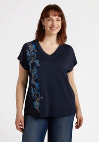 T-shirt a V con maniche corte in tessuto morbido di colore blu navy; presenta ricami floreali e a paisley blu su un lato.