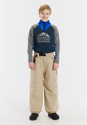 Blauwe en grijze zip-up top met bergafbeelding, gecombineerd met beige sneeuwbroeken, met een elastische tailleband en zakken.