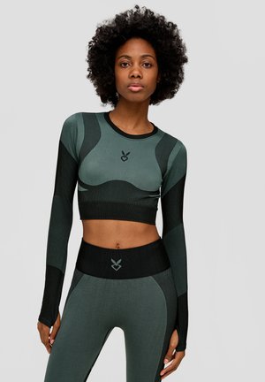 Dark green long-sleeve crop top with ribbed texture and black accents. High-waisted leggings with similar color scheme and logo detail at the waist.