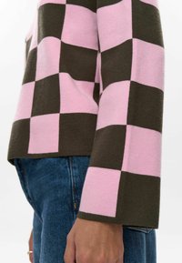 Pullover lavorato a maglia con motivo a quadri in rosa e marrone scuro. Presenta maniche lunghe con un leggero svaso e un collo rotondo.