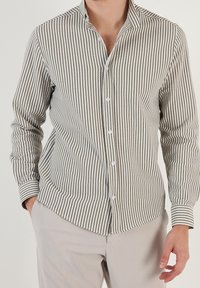 Camicia a righe verde oliva e bianca, con una vestibilità slim, maniche lunghe e colletto a punta. Tessuto liscio con una sottile texture.