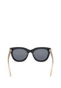 Sluneční brýle ve stylu kočičích očí s černým acetátovým rámem, šedými zbarvenými čočkami a zlatými kovovými akcenty na spáncích. Hladký povrch s elegantním designem.