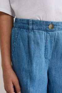 Hele sinised teksapüksid voldikutega, vöö nupuga ja küljetaskutega. Kangas on pehme tekstuuriga ja ühtlase, peene mustriga.