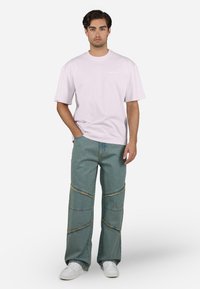 Lichtroze T-shirt met korte mouwen en een ronde hals. Gecombineerd met ruime vervaagde blauwe jeans met contrasterende stiksels en uitgerafelde randen. Witte sneakers.