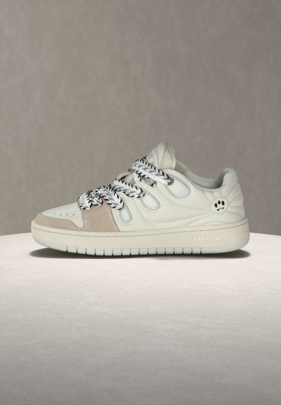 Λευκό και μπεζ αθλητικό παπούτσι με κορδόνια από μαύρο-άσπρο σχοινί, λογότυπο με αποτύπωμα πατούσας στη φτέρνα και την επιγραφή "BARROW" στη μεσαία σόλα.