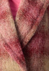 Wollen jas, bestaande uit een mengsel van roodachtige en beige vezels, met een zachte, fluffy textuur en een sjaalkraag en overlappend voorkantontwerp.