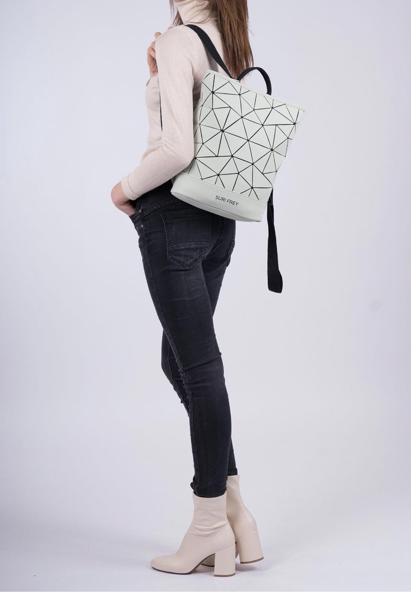 Le sac à dos présente un extérieur gris clair avec un motif géométrique, des accents noirs et une poignée supérieure robuste. Des bretelles noires s'étendent des côtés.