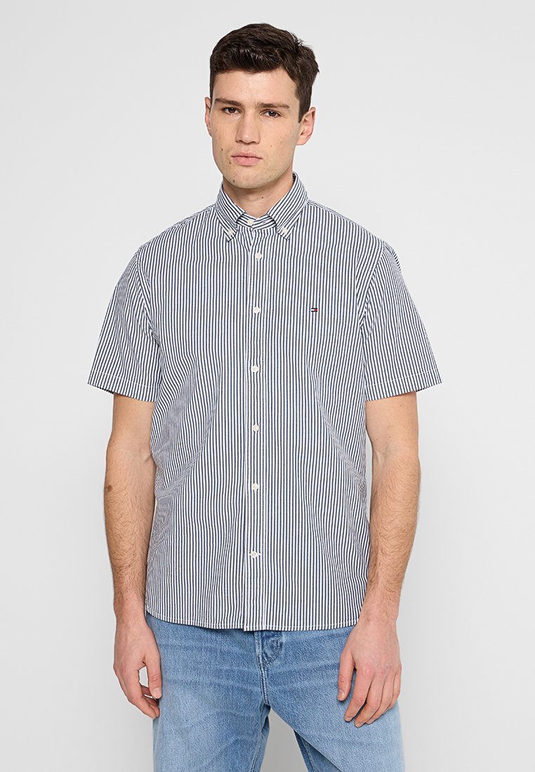 Chemise à manches courtes en bleu et blanc à rayures verticales, en coton, avec un col et un petit logo sur la poitrine.