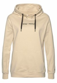Sudadera con capucha beige con bolsillo tipo canguro, cordón en la capucha y texto "stay sassy" en negro. Tejido suave, ajuste relajado y puños acanalados.