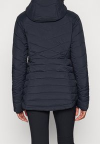 Giacca imbottita blu navy con motivo a zigzag, cappuccio integrato e tasche laterali, realizzata in materiale resistente all'acqua.