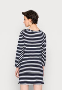 Vestido de mangas longas às riscas azul-marinho e brancas, com um corte descontraído, decote redondo e aberturas laterais para um detalhe adicional.