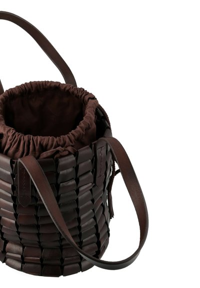 Borsa a secchiello in pelle intrecciata marrone con chiusura a coulisse, tracolle piatte in pelle e una fodera interna liscia. Forma strutturata e rotonda.