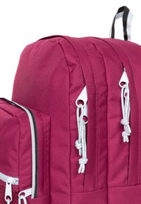 Bordový látkový batoh s dvěma hlavními přihrádkami, bílým kováním a detaily na stažení. Texturovaný povrch s kontrastním zipem.