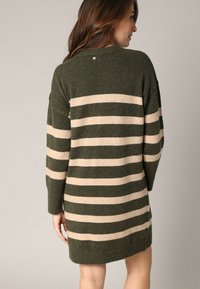 Übergroßes Strickkleid in Dunkelgrün mit beigen Streifen. Hergestellt aus weichem Material, mit einem Rundhalsausschnitt und geripptem Saum.