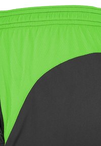 Sportschoenen met een felgroen mesh-paneel en een glad zwart stof. Het ontwerp bevat gebogen lijnen en een elastische tailleband.