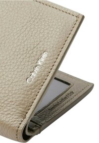 Portafoglio in pelle beige con texture, logo argento, finestra per ID trasparente e dettagli di cucitura visibili. Design aperto per un facile accesso.