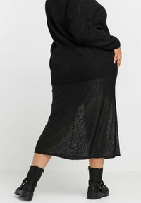 Mustapaitainen neule, yhdistettynä mustaan hameeseen, jossa on hillitty eläinkuos, nilkkurit, joissa on vahva pohja ja soljellinen yksityiskohta.