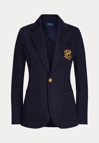 Blazer bleu marine pour femme avec bouton doré, deux poches avant et logo brodé en or sur la poche poitrine gauche.
