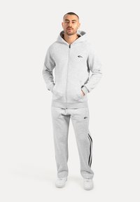 Grijze zip-up hoodie en bijpassende sweatpants, gemaakt van zachte stof. Heeft een logo op de borst en zijstrepen op de broek.