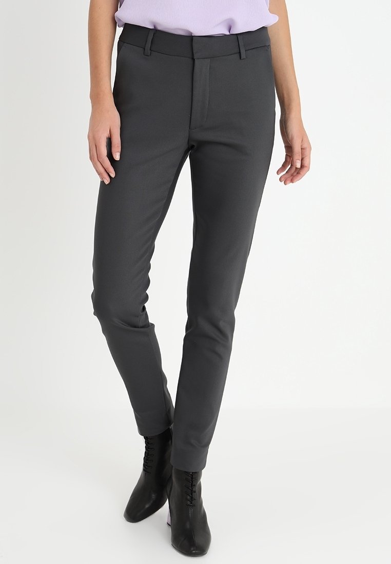 Grijze op maat gemaakte broek met een getailleerd ontwerp, een gladde textuur en een platte voorkant. Voorzien van riemlussen en een subtiele glans. Zwarte schoenen maken de outfit compleet.