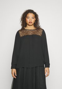 Maglietta nera a maniche lunghe con un pannello in pizzo all'collo, caratterizzata da una vestibilità rilassata e una texture liscia. Accentuata da polsini con bottoni.