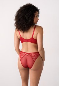 Rotes Spitzenunterwäscheset mit einem BH mit verstellbaren Trägern und passenden transparenten Unterhosen mit floralem Muster und Schlüssellochdetails auf der Rückseite.