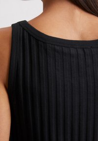 Czarny prążkowany top na ramiączkach z szerokim dekoltem i miękką teksturą, podkreślający pionowe linie w materiale, co nadaje dopasowany wygląd.