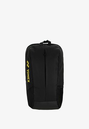 Zaino nero Yonex con manico superiore, cerniera frontale verticale, tasca laterale in rete e logo giallo sul lato sinistro.