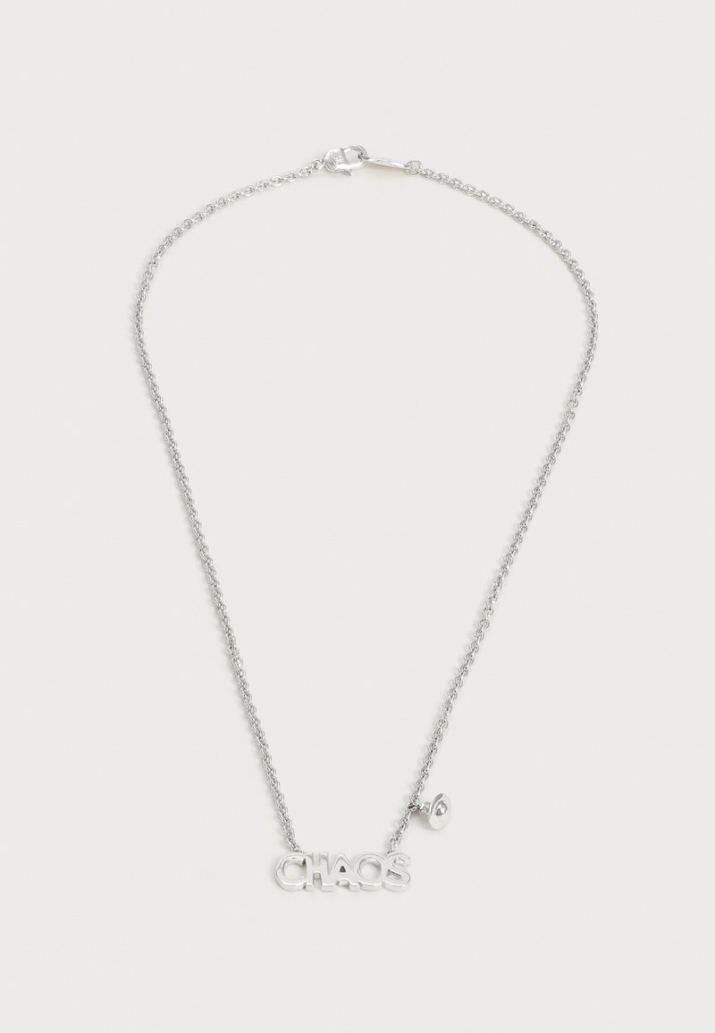 Collier à chaîne argentée avec un fermoir, un pendentif portant le mot « CHAOS » et un petit charm suspendu sur un fond uni.