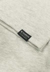 Lichtgrijze gebreide stof met een zachte textuur, met een zwart label waarop "GARCA" in witte tekst staat, aan een opgevouwen rand.