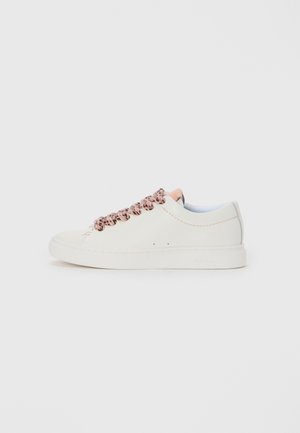 White low-top sneaker with pink and black patterned laces and peach-colored accents on the tongue and stitching, side view on a plain background.