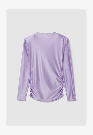 Maglietta a maniche lunghe di un leggero lilla, realizzata in tessuto liscio e lucido. Presenta dettagli arricciati sui lati e un collo rotondo.